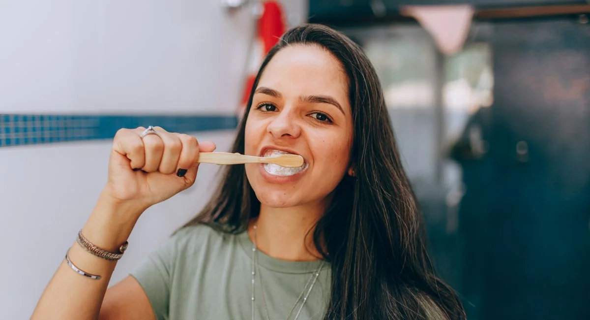 Portrait of a young woman brushing her teeth indoors, promoting dental hygiene.