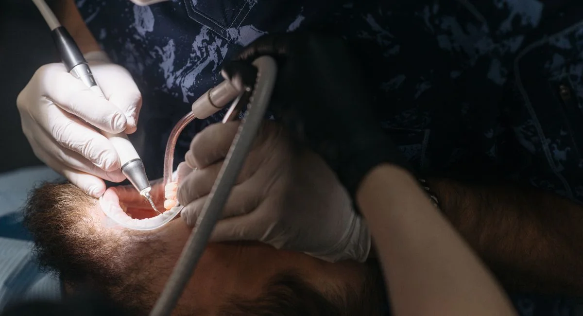 Dentist performing a procedure on a patient with dental tools inside a modern clinic.
