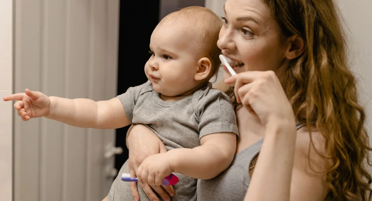 A joyful moment as a mother teaches her baby toothbrushing, fostering healthy habits.