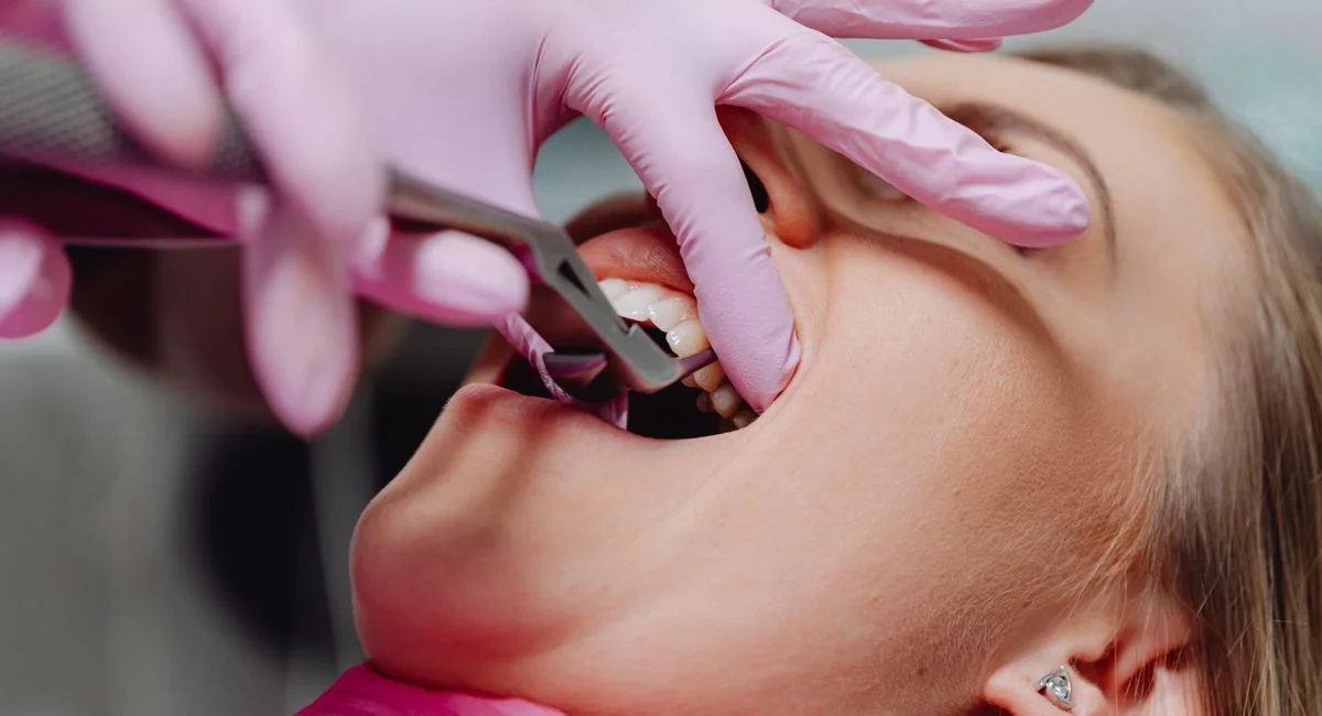 A patient receiving dental care, showcasing pink gloves and dental tools in a clinic setting.