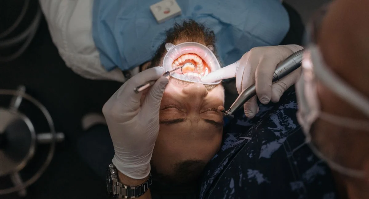 A dentist performing a thorough dental examination on an adult male patient in a clinic.