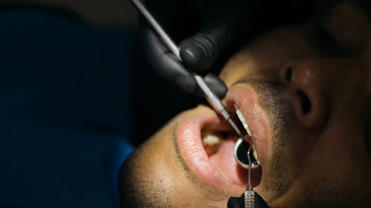 Un professionnel examine la bouche d’un patient avec des instruments dentaires