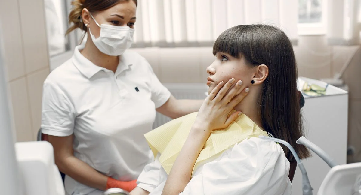 A dentist examining a young woman with toothache in a dental clinic.