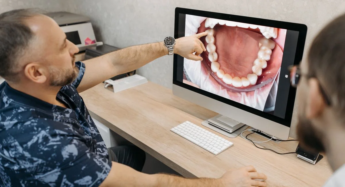 Dentist explains dental condition using intraoral images on a computer screen.