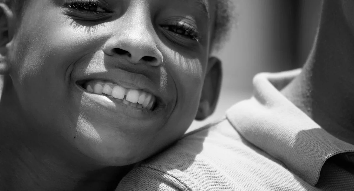 Grayscale close-up of a cheerful child smiling, embodying happiness and innocence.