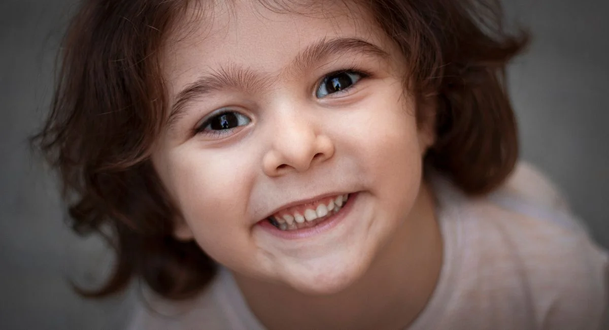 Close-up portrait of a cheerful child smiling warmly, showcasing joy and innocence.