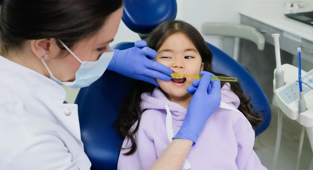 Female dentist examines a young girl's teeth in a modern dental clinic.