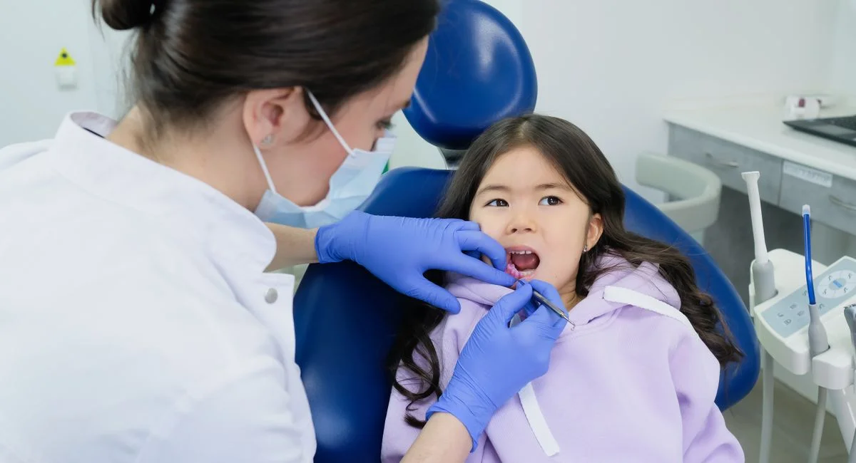 Young girl receives dental checkup from a female dentist in a clinic.