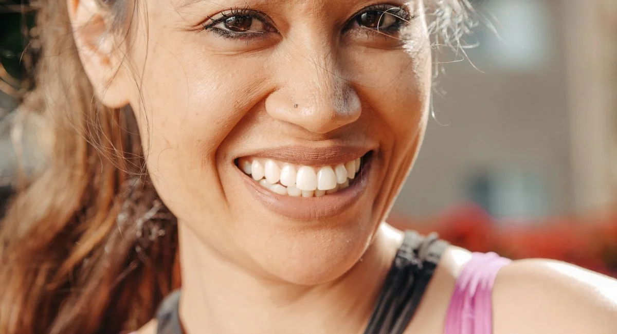 Close-up of a smiling woman enjoying a sunny day outdoors.